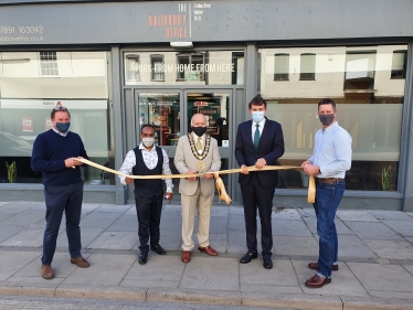 John holding the opening ribbon, next to Salisbury Mayor on his left, Cllr Hoque on his right and Salisbury Office team.  